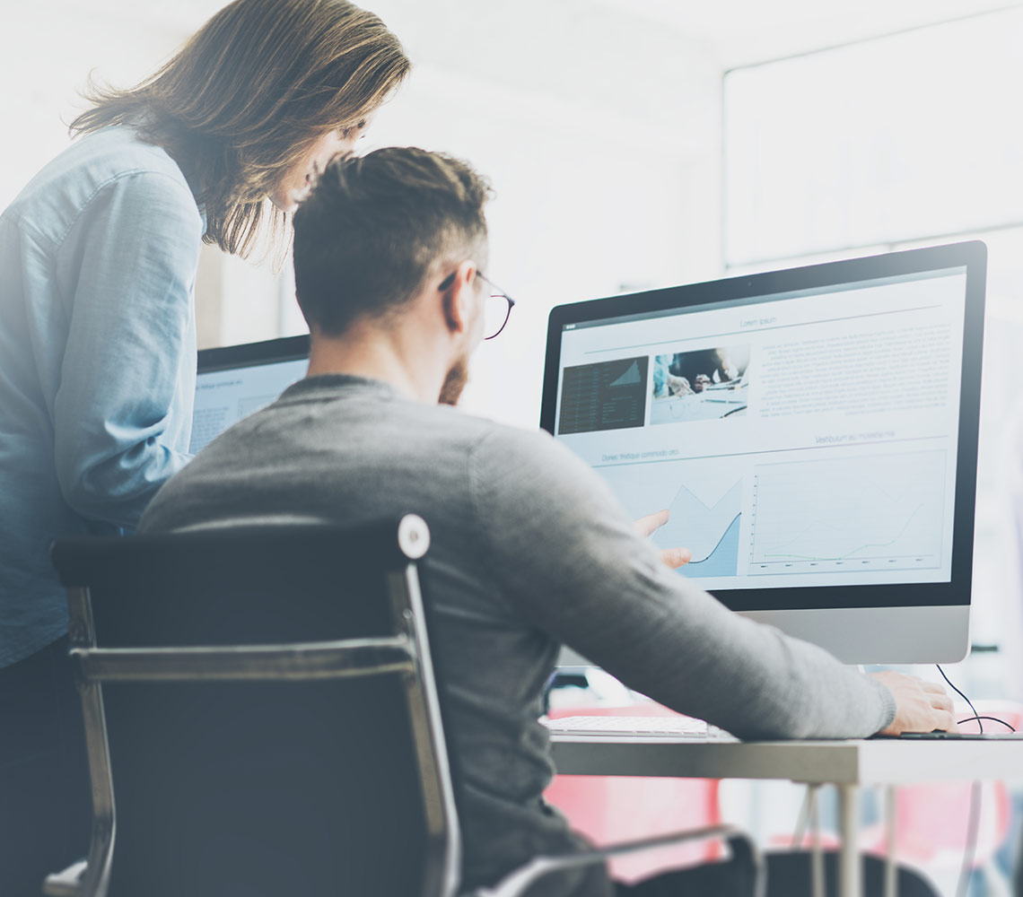 Deux collègues discutant des informations présentés à l'écran de l'ordinateur